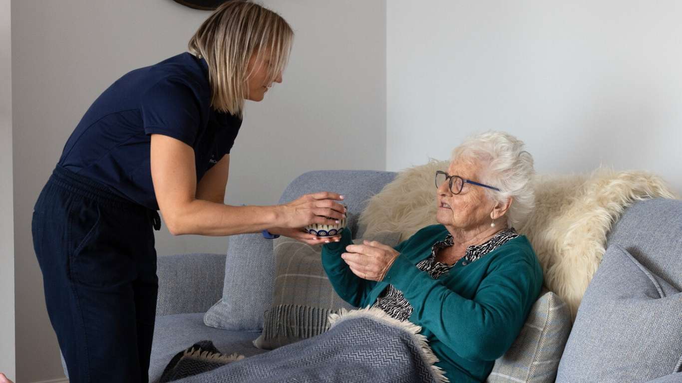 A photo of a carer passing a drink to a client.