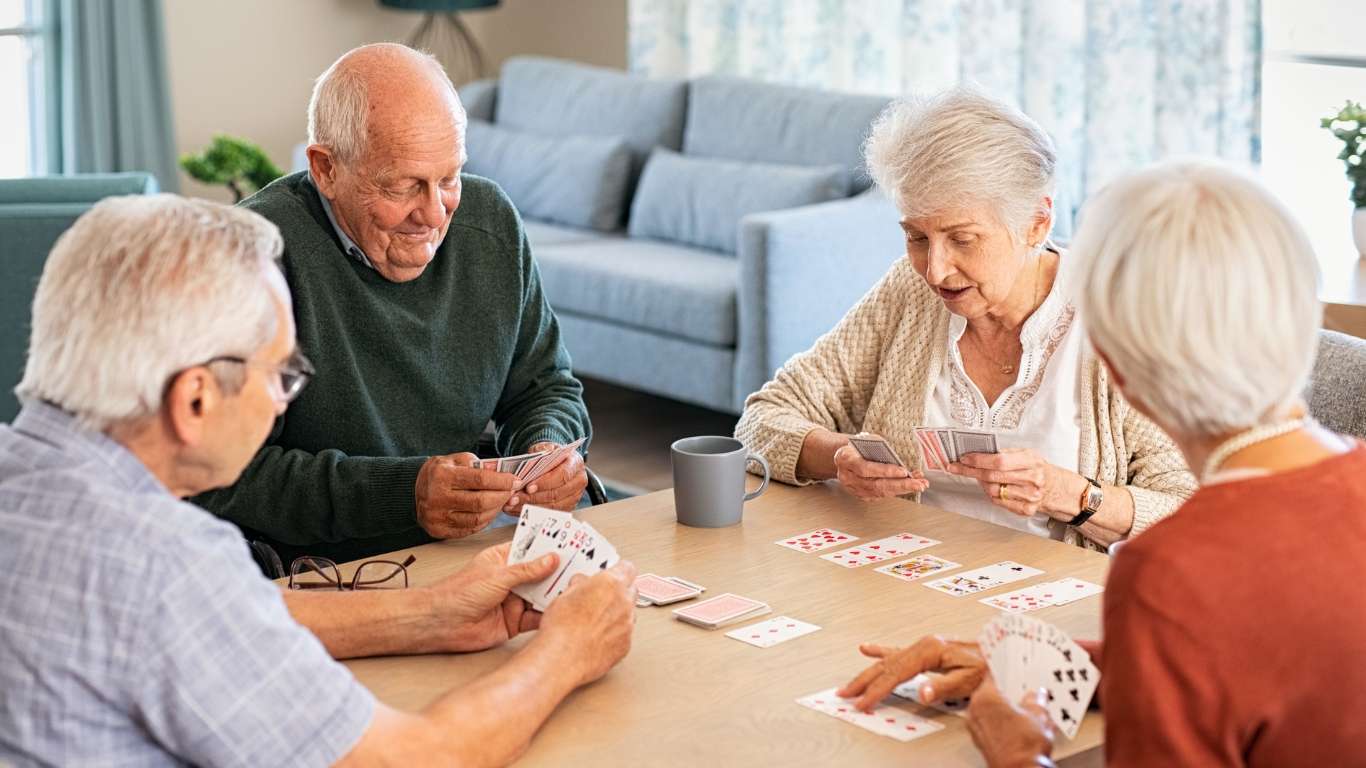 A group of elders playing a card game at a table.