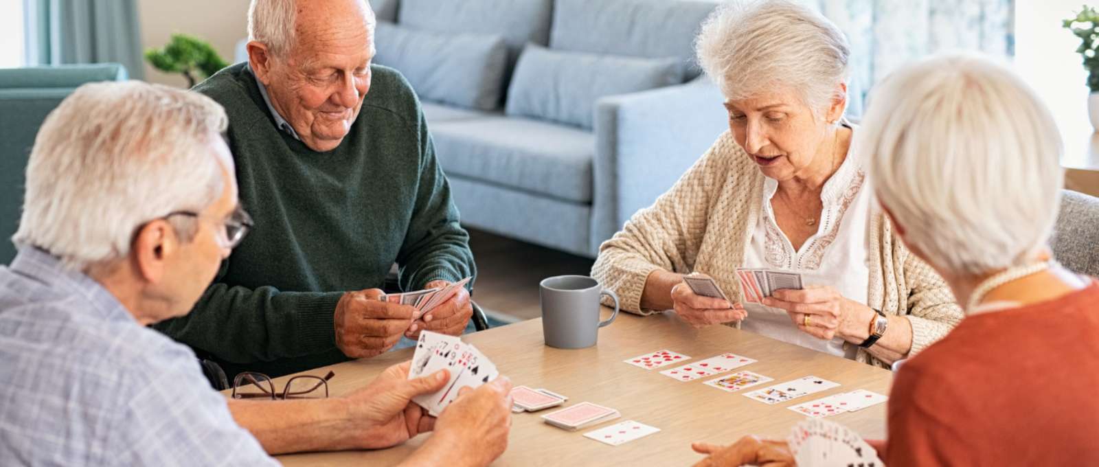 A group of elders playing a card game at a table.