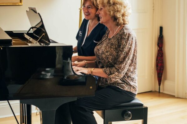Bright Carer and client playing piano Elderly in-home care, Bright Carer and her client playing piano together