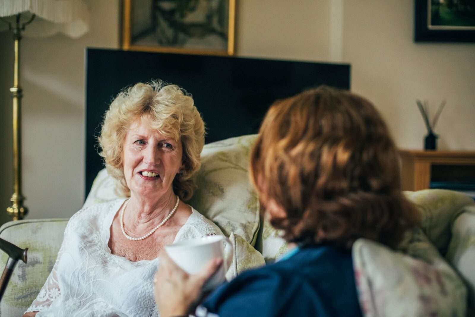 Bright Carer drinking tea with her client