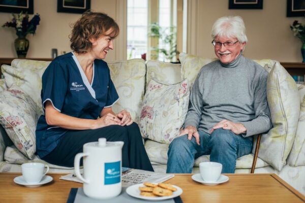 Bright Carer and male client on sofa(6) Bright Carer and her client having tea on the sofa