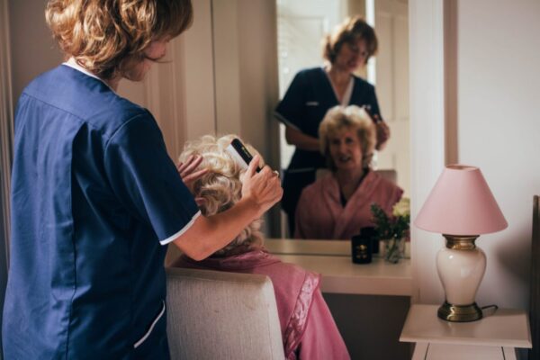 Bright Carer combing the hair of her client in the morning