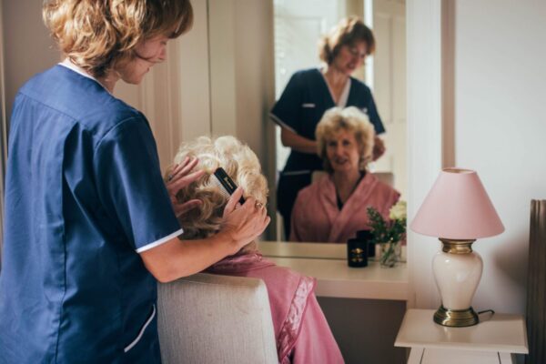 Live-in home care - Bright Carer combing the hair to her client in the morning