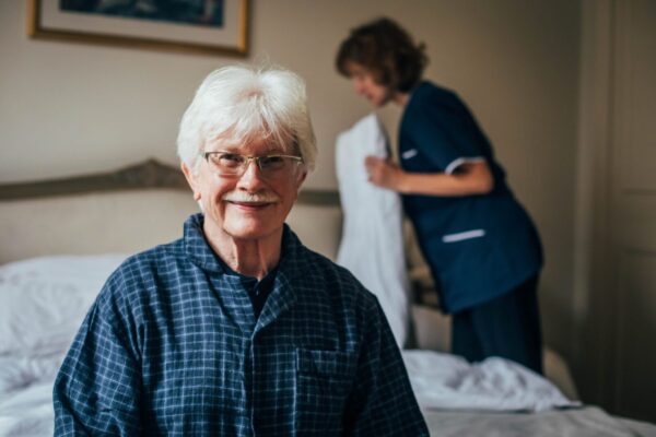 Bright Care's client smiling while his Bright Carer adjusts his bed