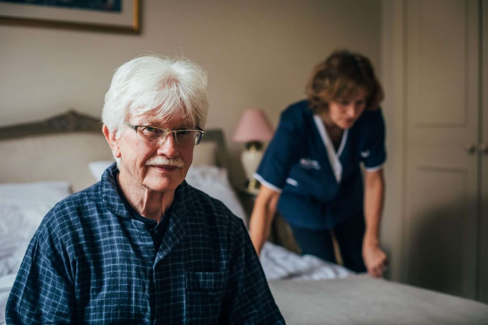 Bright Care's client smiling while his Bright Carer adjusts his bed