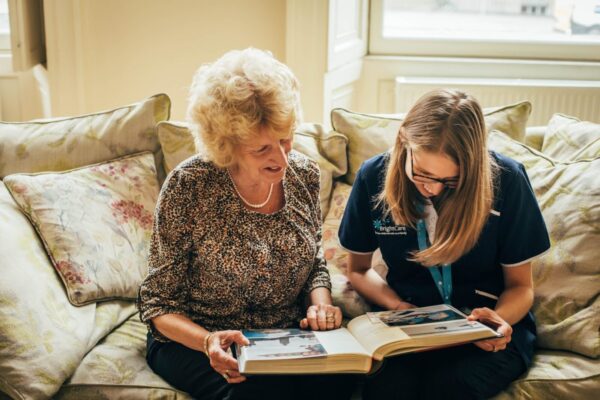 Bright Carer and client looking at photo album
