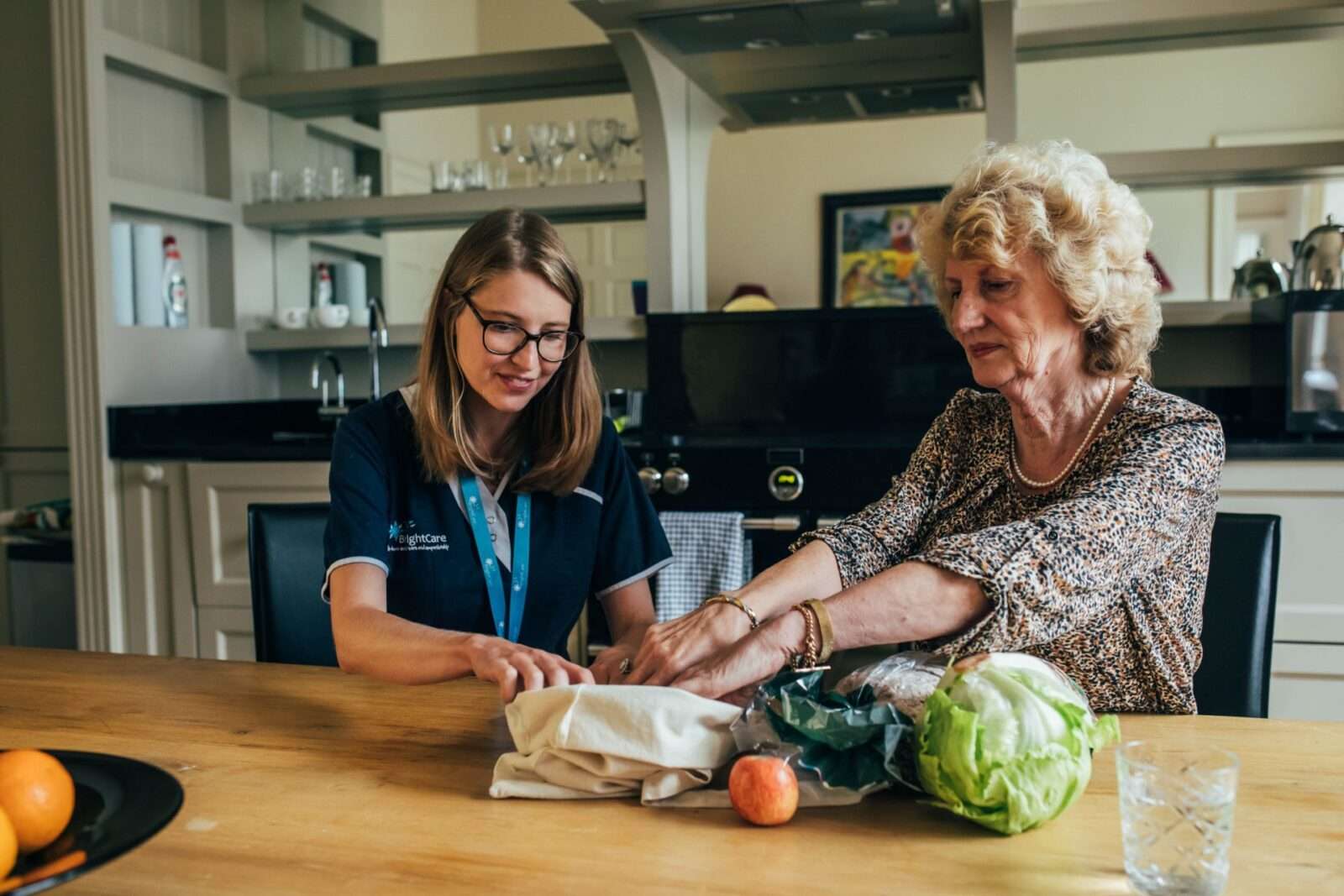Bring Carer and her client unpacking the grocery shopping in the kitchen
