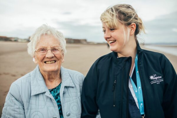 Client and Bright Carer walking on the beach