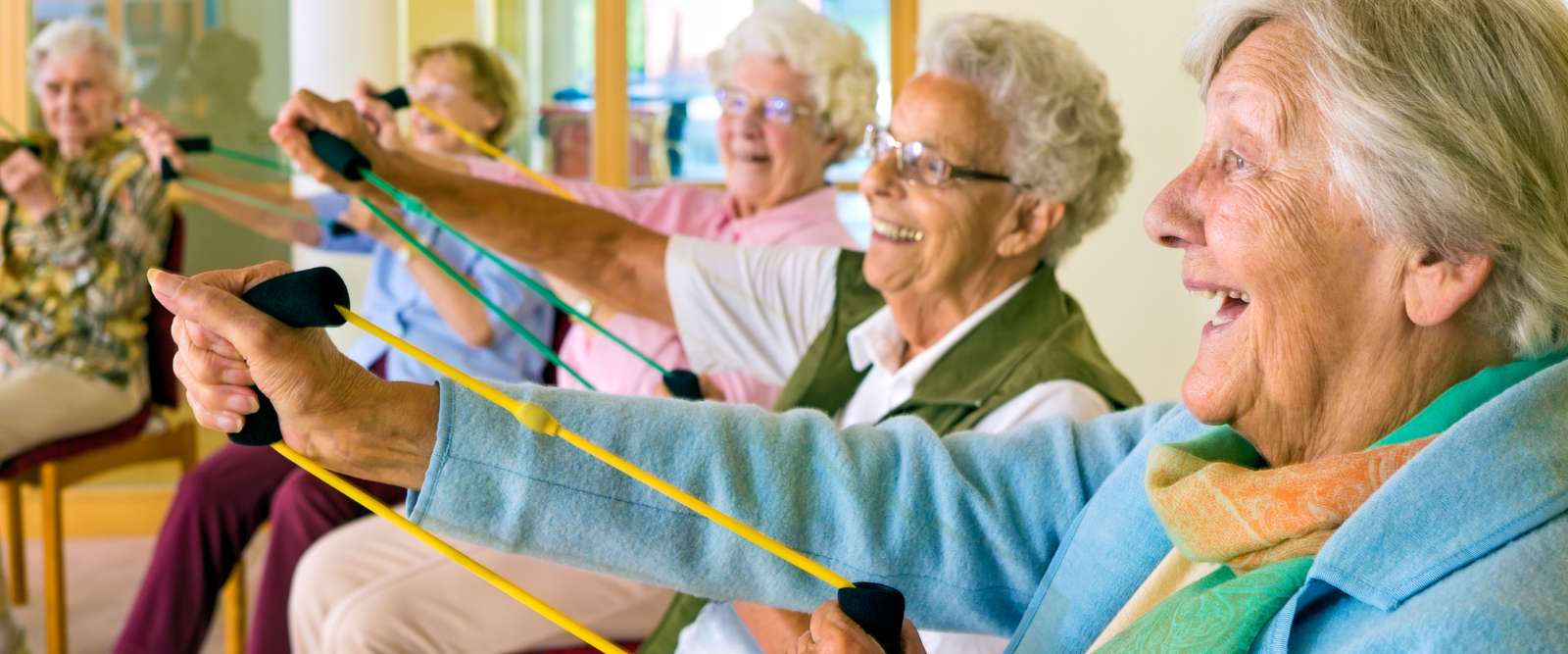Happy elderly people exercising with resistance bands as part of elderly fitness programmes