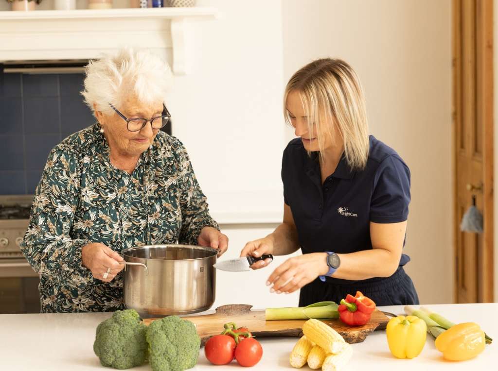 One of our Bright Care carers helping one of our elderly clients with cooking.