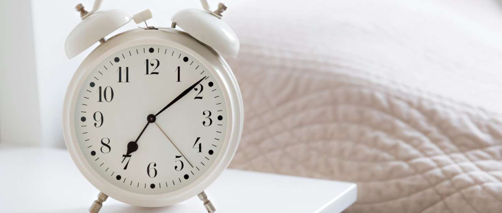 An alarm cock sitting on a bedside table.