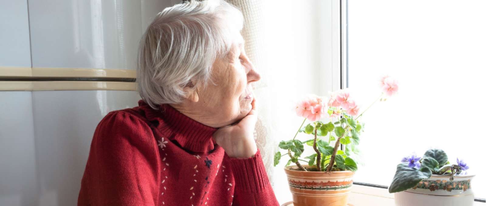 Elderly woman looking out of the window.